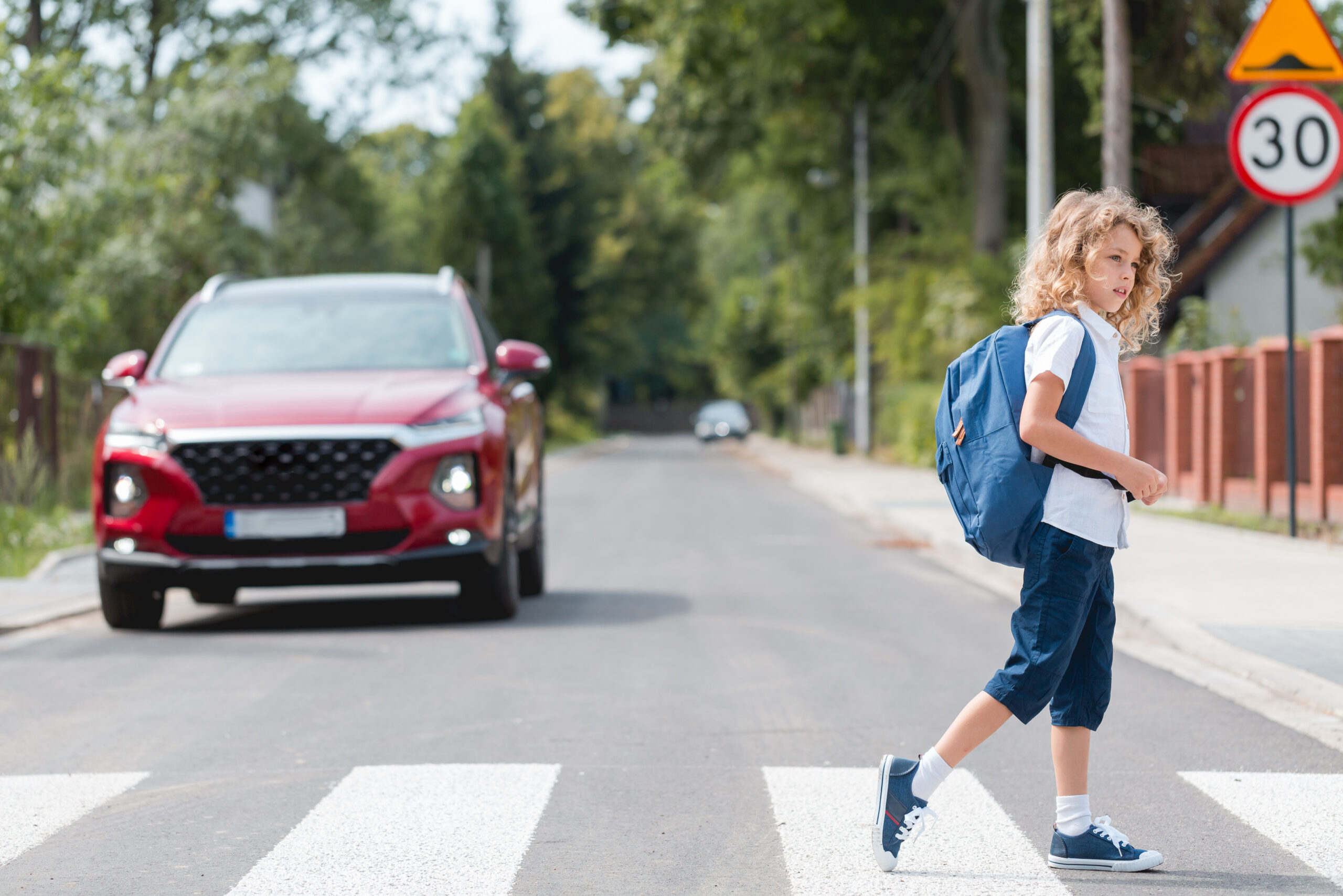 Child crossing road at school zone pedestrian crossing with car approaching in NSW school zone